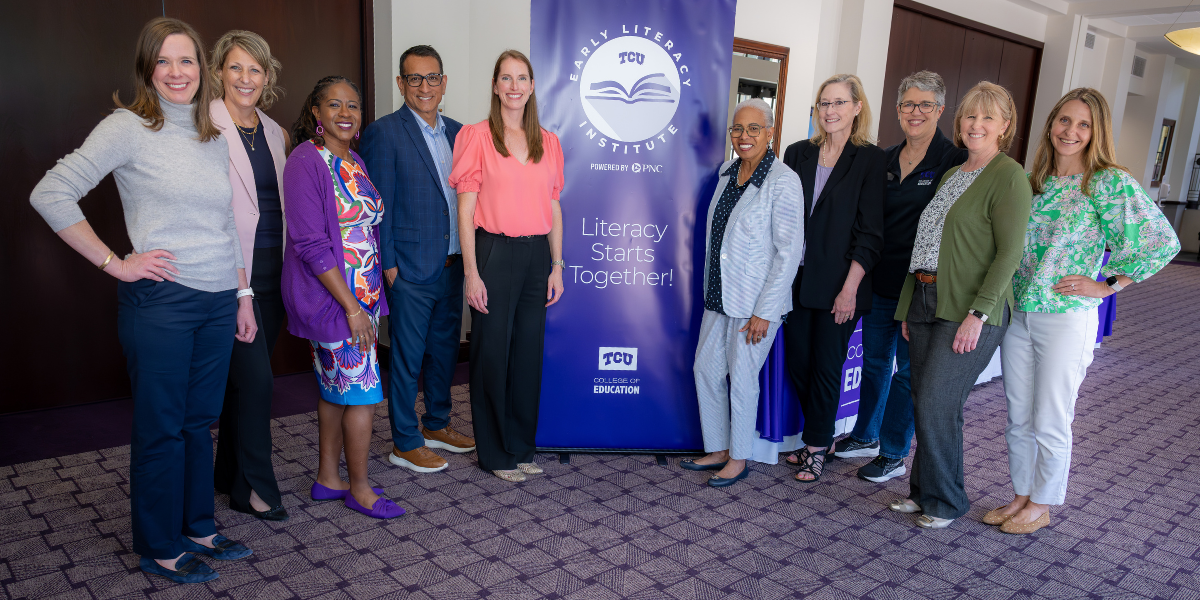 TCU Professors Kathleen Kyzar, Robin Griffith, Endia Lindo, Dean Frank Hernandez, Jan Lacina, Lori Kimball, Michelle Bauml and Jennifer Smith stand with a representative from PNC Bank and Dr. Gloria-Ladson Billings. In the center is a large purple banner featuring the logos for the TCU Early Literacy Institute Powered by PNC and the College of Educaton along with the phrase: "Literacy Starts Together!"