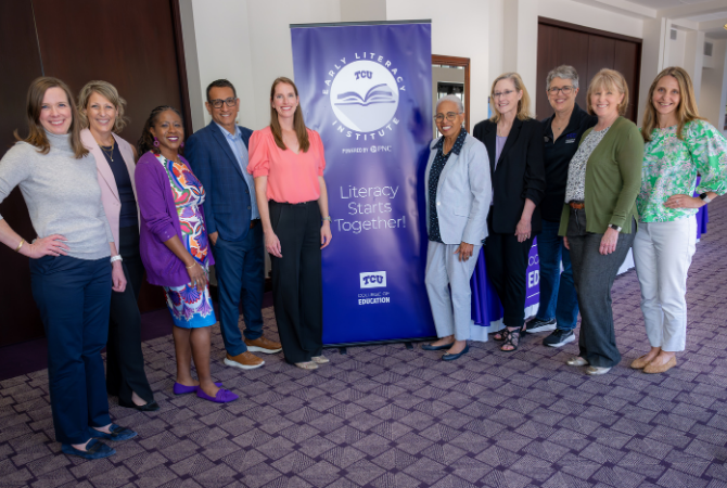 TCU Professors Kathleen Kyzar, Robin Griffith, Endia Lindo, Dean Frank Hernandez, Jan Lacina, Lori Kimball, Michelle Bauml and Jennifer Smith stand with a representative from PNC Bank and Dr. Gloria-Ladson Billings. In the center is a large purple banner featuring the logos for the TCU Early Literacy Institute Powered by PNC and the College of Educaton along with the phrase: 