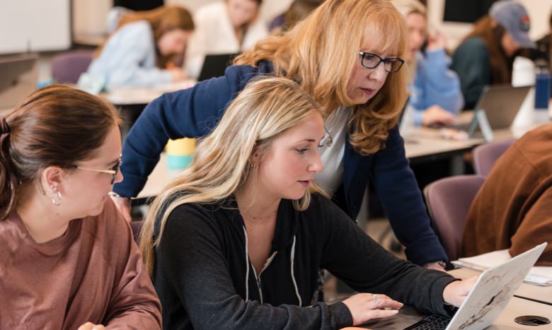 students looking at laptop computer in a classroom