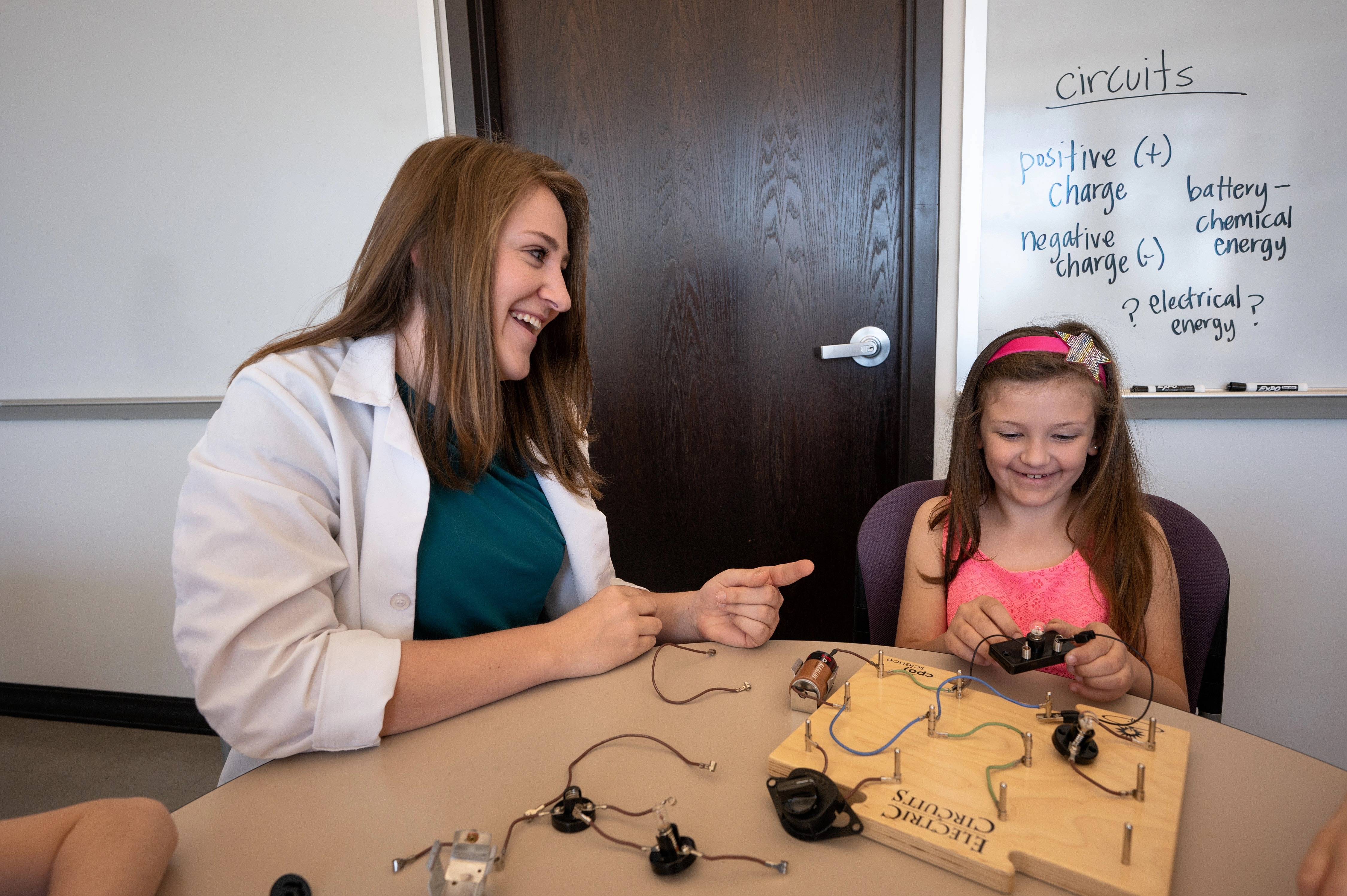 Science teacher and young girl with circuit board