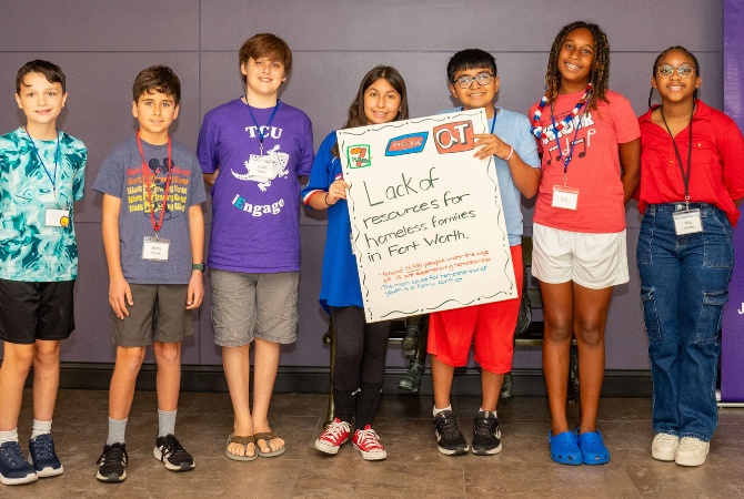 children smiling holding sign with "lack of resources for homeless families in fort worth"