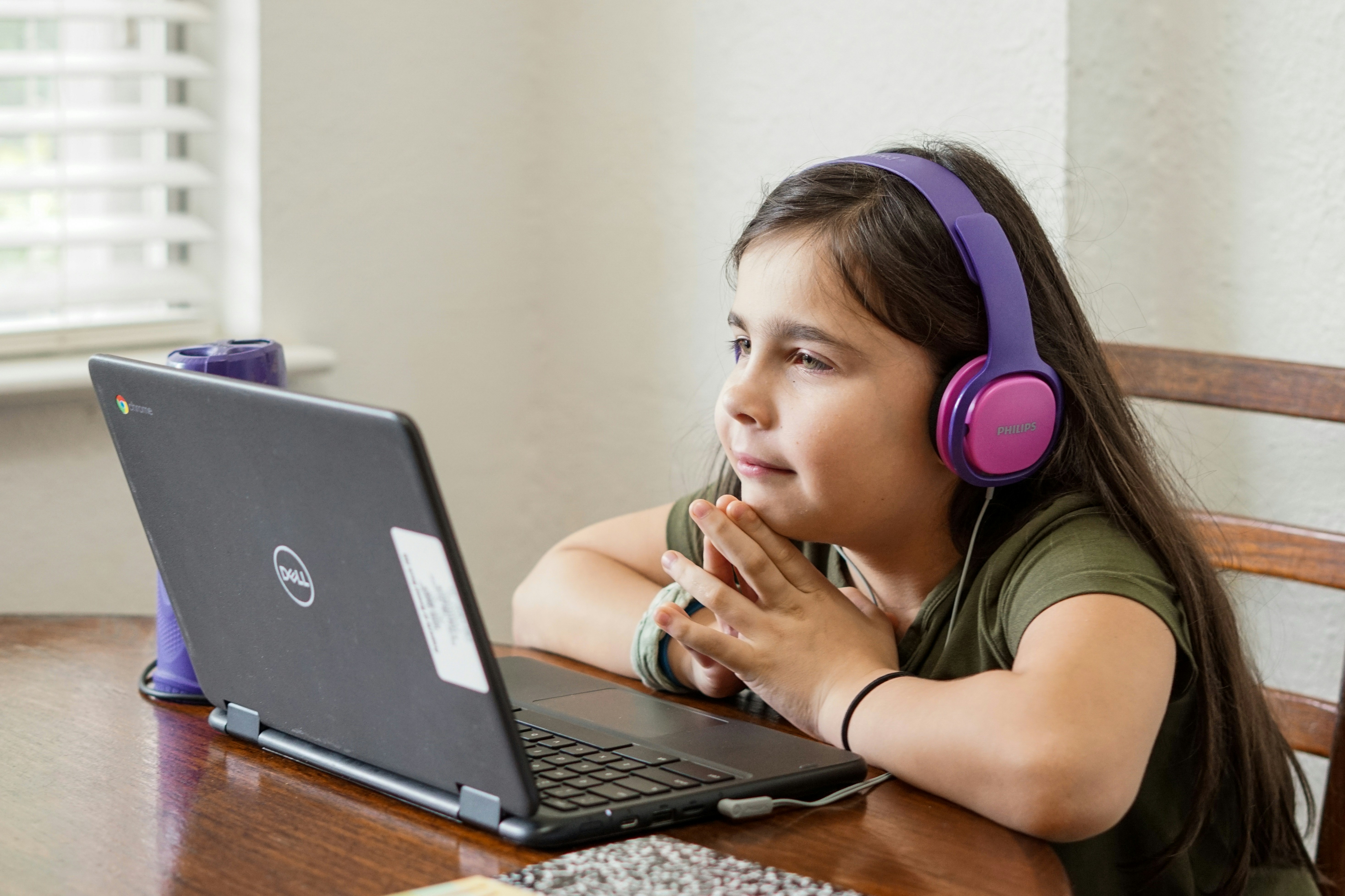 young girl looking at laptop with headphones on