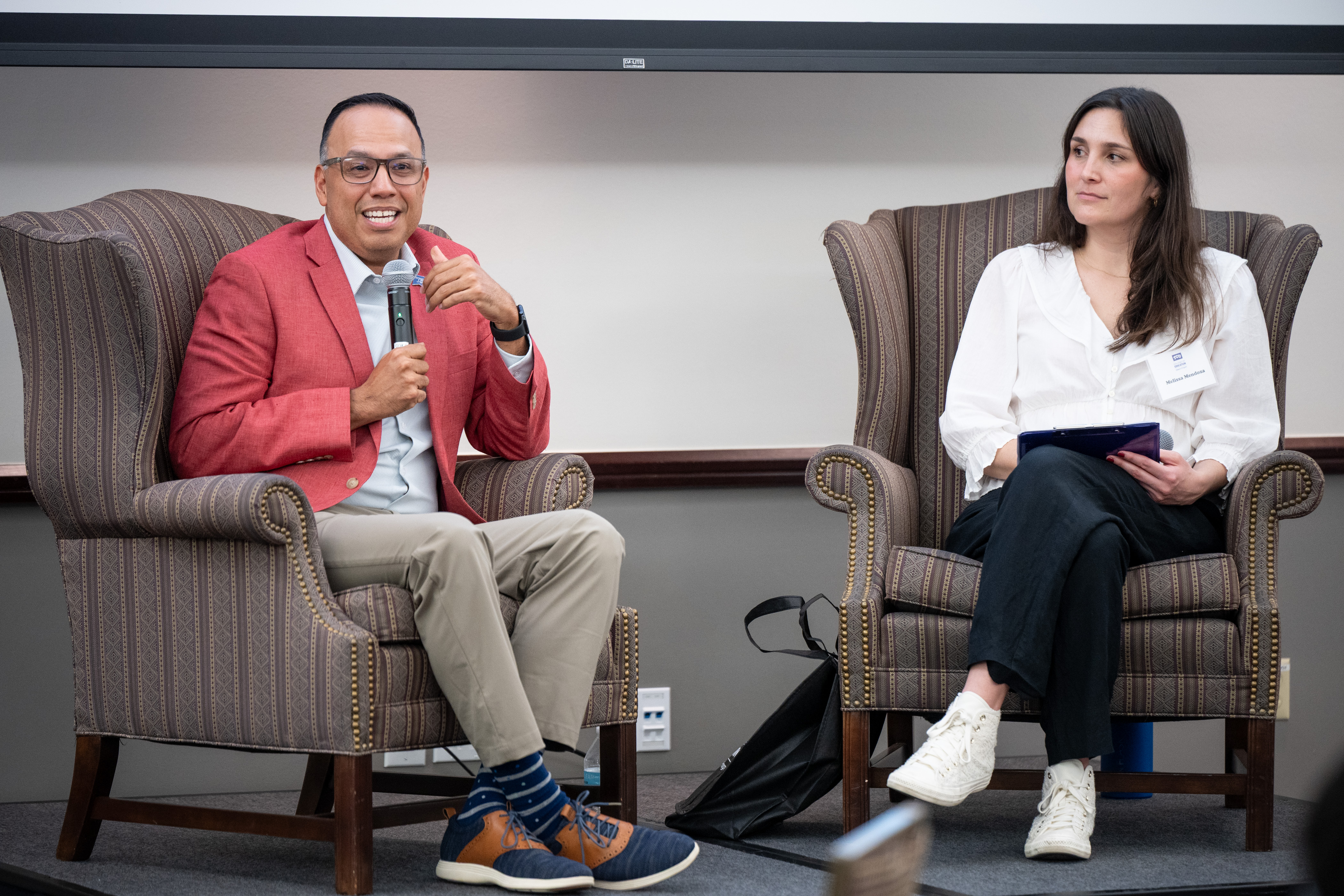 David Saenz and Melissa Mendoza sitting on matching chairs as Saenz speaks with the audience.