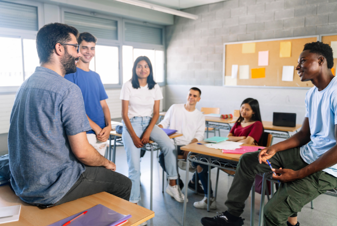 Teenager students listening and talking with friendly young male teacher - Group discussion in High School Education