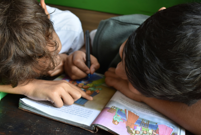 two young boys reading book together